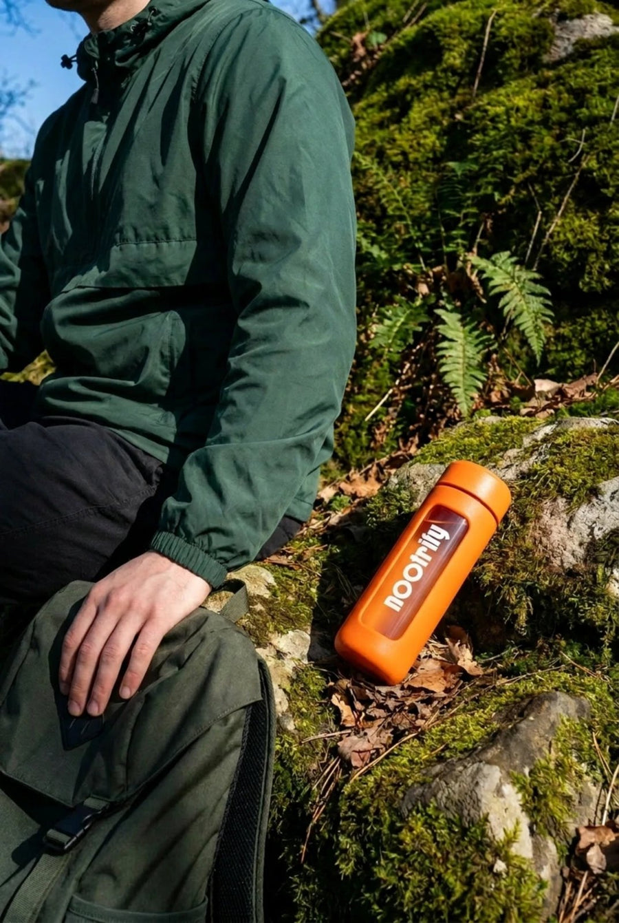 Nootrify bottle on a mossy rock beside a hiker